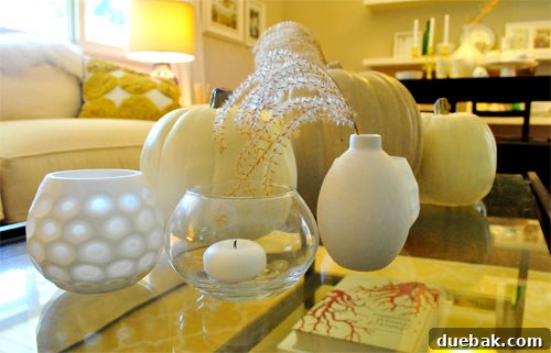 A dining table decorated for Halloween with pumpkins, candles, and candy corn.
