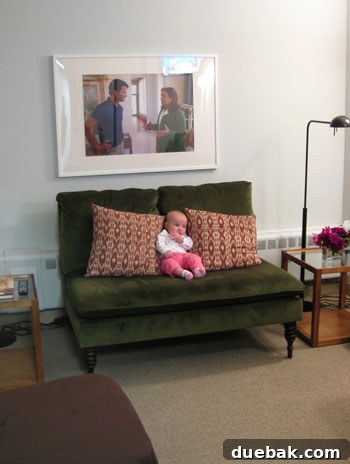 Baby Clara sitting on a small settee in a green room