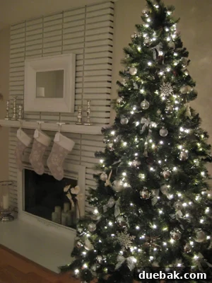 The Festive Evergreen 2 A beautifully decorated Christmas tree with silver ornaments and lights, creating a festive and elegant atmosphere in a home.