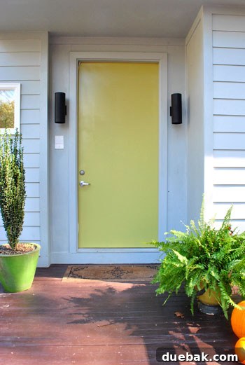 Close-up of the green front door being painted with Cornichon color