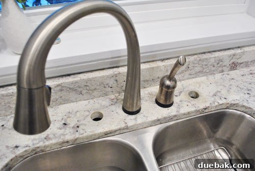 Close-up of two open, unused holes in a granite kitchen countertop