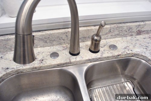 Hands installing a chrome faucet hole cover on a granite kitchen counter