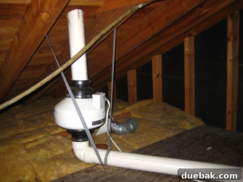 A radon mitigation fan unit installed on the exterior of a home with a pipe venting radon gas.