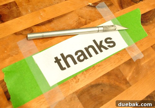 Cutting a homemade stencil of the word THANKS on a cutting board with knife