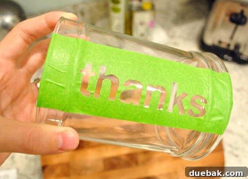 Painter tape THANKS stencil stuck to side of glass apothecary jar for Thanksgiving craft