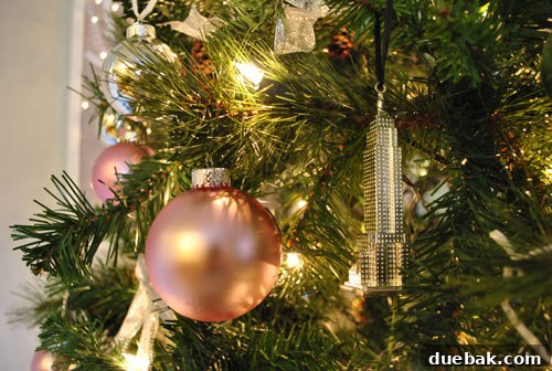 Our Kaleidoscope Christmas Tree 7 A silver Empire State Building ornament hanging on a Christmas tree, symbolizing cherished memories of New York City.