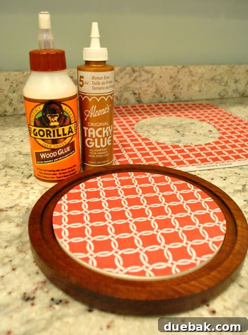 Decorative paper being glued onto the ceramic insert of the cheese plate, showing a red patterned design.
