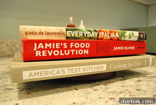 Heavy cookbooks stacked on top of the reassembled cheese plate to apply pressure during glue drying.