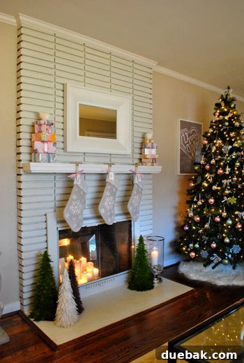 A festive Christmas living room scene with a decorated tree, feather trees, stockings, and faux gifts.