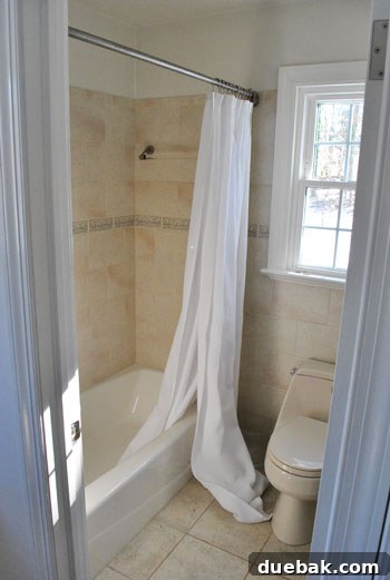 Before: A bunched-up extra long shower curtain pooling on the bathroom floor due to a short tension rod