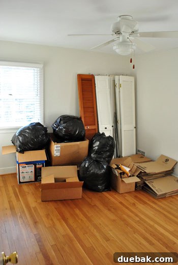 A Sea of Cardboard 3 The same guest bedroom after empty moving boxes have been broken down and organized for disposal or reuse, showing a significantly tidier space.