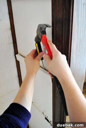 Woman removing wooden shelves with a screwdriver, demonstrating DIY effort