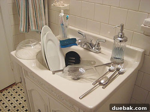 Temporary dishwashing setup in a small bathroom vanity during kitchen renovation, demonstrating a common DIY challenge.