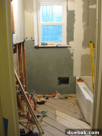Bathroom undergoing renovation, with tiles being meticulously installed on walls and floor, highlighting the messy but rewarding process of a DIY bathroom project.