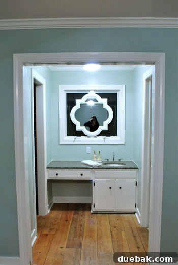 The white-framed bathroom mirror illuminated at night, contrasting beautifully against the dark window background