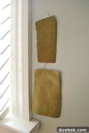 Two fabric swatches taped vertically on a bedroom wall, appearing darker