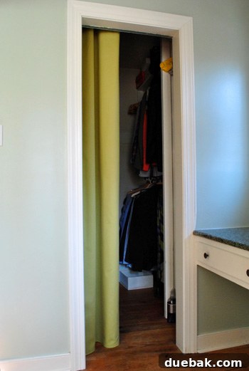 Closet interior with a yellow-green curtain panel pulled to the side, replacing a bifold door