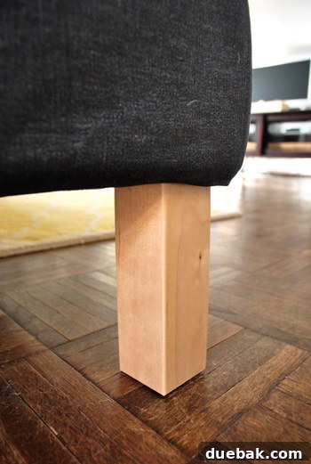 Close up detail of Ikea sectional sofa legs in unfinished blonde wood, showing their sturdy, natural appearance.