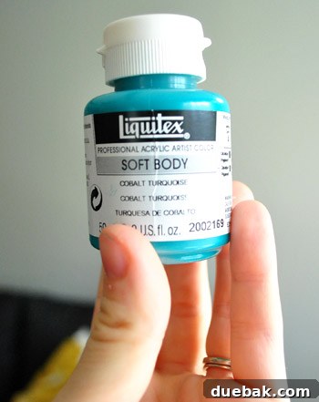 Close-up of a jar of Liquitex Soft Body Acrylic paint in Cobalt Turquoise, a vibrant blue-green color.
