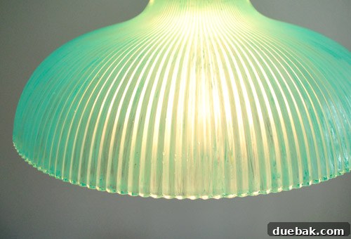 The newly painted turquoise glass pendant light, unlit, showing its transformed appearance and unique character.