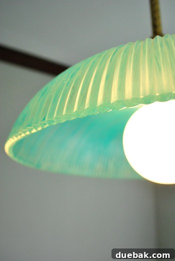 The newly painted turquoise pendant light, now illuminated, casting a soft and inviting glow in the living room.