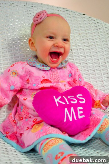 Adorable baby Clara dressed in Valentine's theme, holding a stuffed heart.