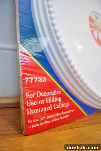 Instant Elegance: Concealing Drywall Cracks with Ceiling Medallions 4 A person holding a white ceiling medallion up to the cracked ceiling area, visualizing the placement before installation.