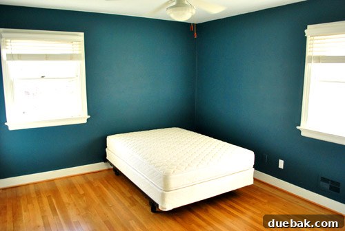 Guest room with dark teal walls viewed from the hallway, highlighting the room's bold transformation.