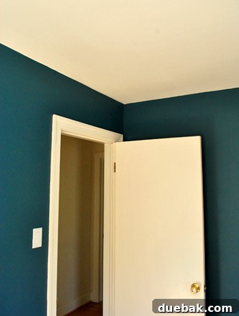 Guest room after painting, showing the dramatic dark teal walls and anticipating future decor.