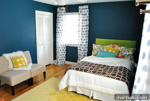 Our guest room showcasing a neatly made bed with a vibrant green headboard, yellow rug, and two slipper chairs, offering a much-improved look.