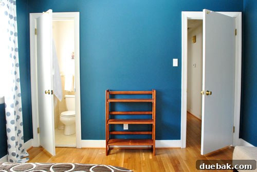 A different angle of the guest room, highlighting the balanced layout with the bed, rug, and slipper chairs, along with the newly hung curtains.