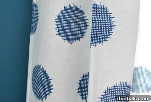 Close-up of the light-colored Ikea curtains in the guest room, showcasing their extra-long length and elegant drape, hung high to enhance room height.