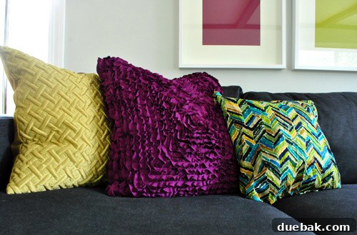 Plush Emerald Shag: Living Room's Green Oasis 7 Close-up of a gray sectional sofa with a new ruffled purple pillow.