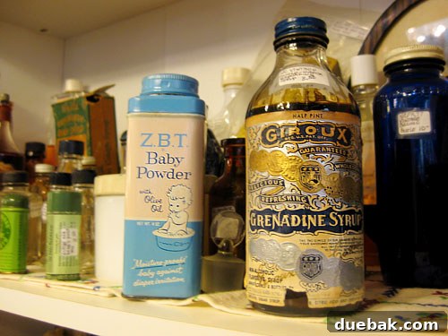 A shelf displaying a collection of vintage bottles, old toiletries, and 'snake oil' packaging.