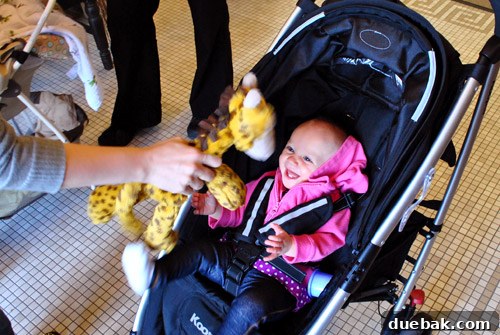 A young child, Clara, beaming with excitement while holding her new giraffe Jellycat toy.
