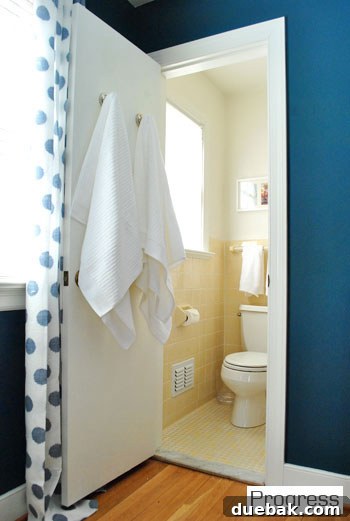 Updated guest bathroom with new mirror, towel hooks, art, and bright shower curtain