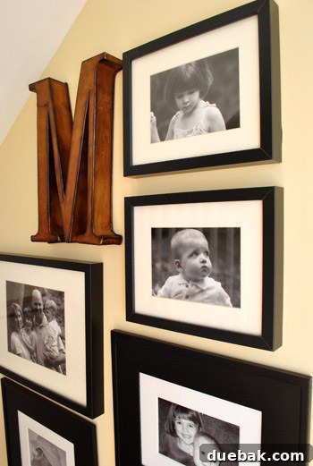 Personalized gallery wall on the staircase, featuring framed photos and an initial 'M'