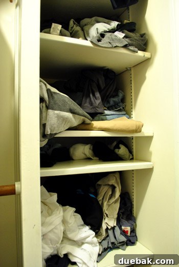 Another view of the messy closet with clothes overflowing