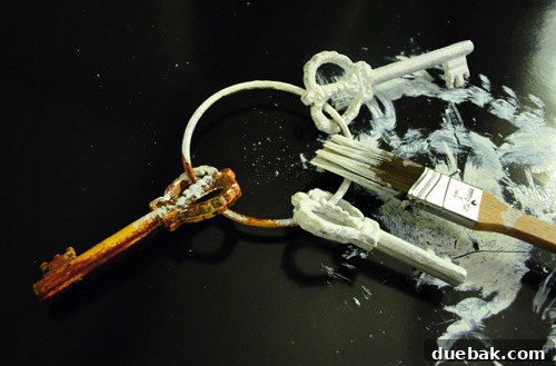 Large Painted Metal Keys on Display 3 Close-up of an old iron key being painted white by hand.