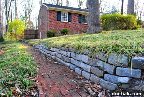 First Look: Our New Home's Exterior 7 Sloped area of the front yard densely planted with liriope (monkey grass) above and below a stone wall
