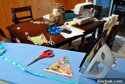 Iron-on hem tape being used to attach fabric flags to a ribbon.