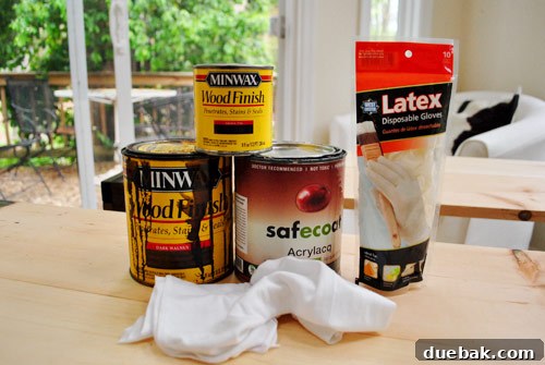 Collection of wood staining supplies including Minwax Wood Finish stains, rags, latex gloves, and an eco-friendly sealer, ready for application.