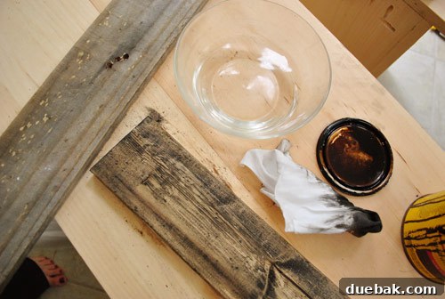 Applying watered-down stain to a damp board to create a lighter, more translucent stain effect, achieving a faded, weathered look.