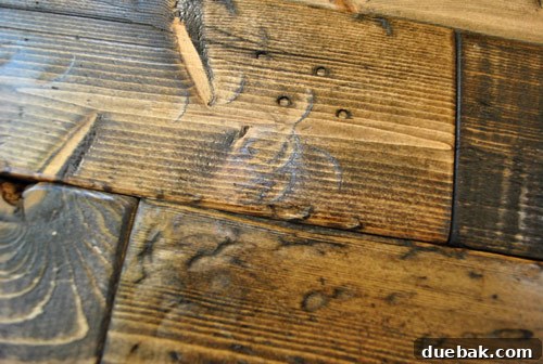 Visible hammer marks on a distressed wood DIY project after applying a dark stain finish, highlighting the textured surface.