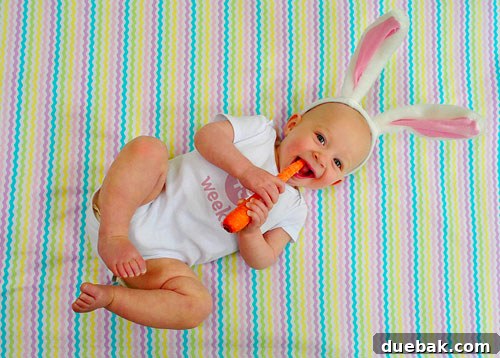 Easter Steals 14 Clara posing for her weekly photo against a fabric background, holding a real carrot like a bunny