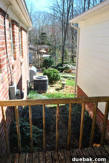 A narrow alleyway leading directly to a neighbor's back deck, highlighting a lack of privacy.