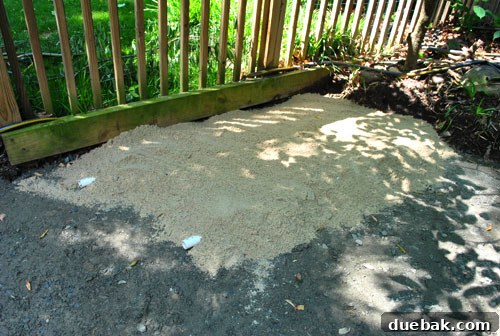 Sand being dumped over PVC pipes to create a level bedding layer for pavers