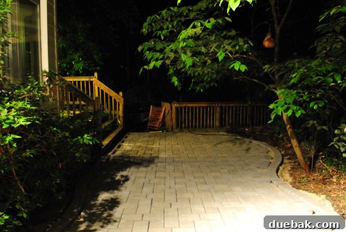 Partially completed paver patio at dusk, showing the main section laid with full pavers