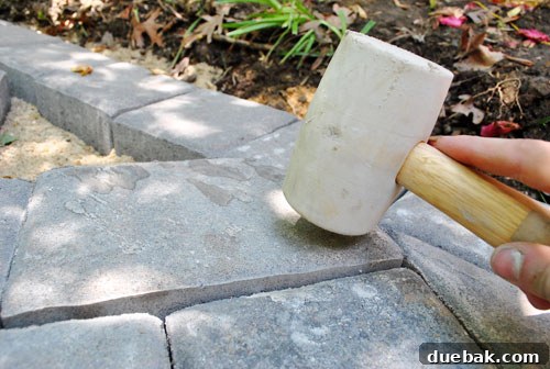 DIY Paver Patio: Transform Your Backyard 8 Tapping pavers into place with a rubber mallet