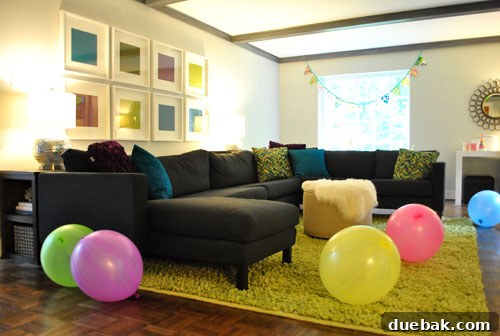 Living room decorated with giant balloons and a handmade fabric flag banner for a first birthday party.